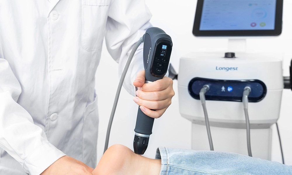 A clinician holding the shockwave handpiece beside the machine